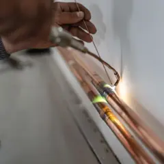 Ręczne lutowanie rur miedzianych, podkreślające twardość miedzi i precyzję pracy instalatora.