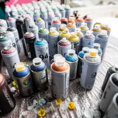 Mnóstwo puszek farby w sprayu, gotowych do akcji. Zastanawiasz się, ile schnie farba w sprayu? Tutaj znajdziesz odpowiedź.