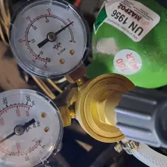 Manometr wskazuje ciśnienie gazu do lutospawania. Zielona butla z etykietą UN 1956 sugeruje, że jest to gaz sprężony.