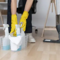 Ręce w żółtych rękawiczkach sięgają po butelki z płynem czyszczącym, gotowe do usunięcia farby w sprayu.
