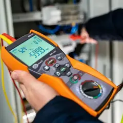 Elektryk wykonuje pomiary elektryczne krok po kroku za pomocą miernika.