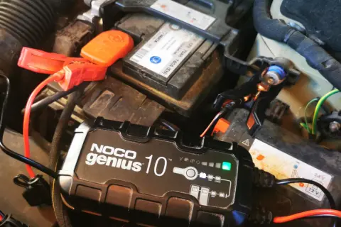 Ładowarka NOCO Genius 10 podłączona do akumulatora samochodowego. Czy można ładować akumulator podpięty do auta? Tak, to bezpieczne.