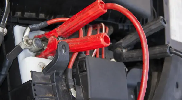Czerwone klemy podłączone do akumulatora. Zobacz, jak podłączyć klemy, aby uruchomić auto.