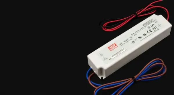 Zasilacz LED z oznaczeniami napięcia i mocy. Urządzenie ma białą obudowę i kable w kolorach czerwonym, czarnym, brązowym i niebieskim.