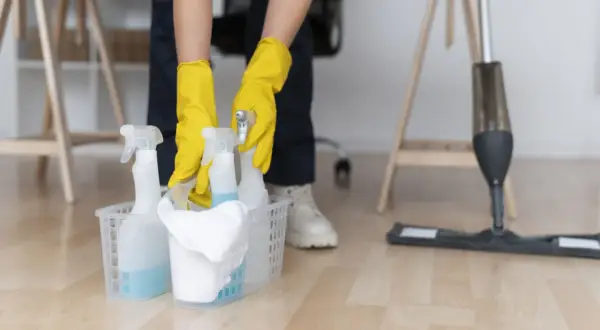 Ręce w żółtych rękawiczkach sięgają po butelki z płynem czyszczącym, gotowe do usunięcia farby w sprayu.