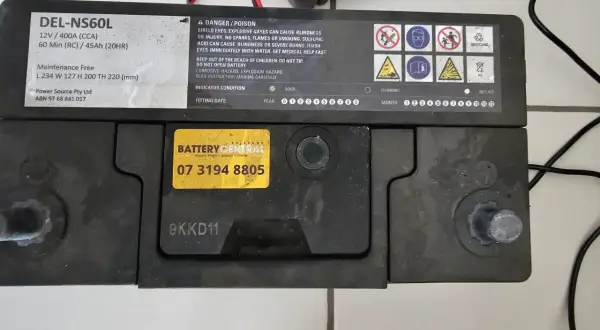 Akumulator DEL-NS60L, podłączony do ładowarki, lekko bulgocze podczas ładowania.