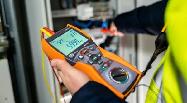 Elektryk wykonuje pomiary elektryczne krok po kroku za pomocą miernika.