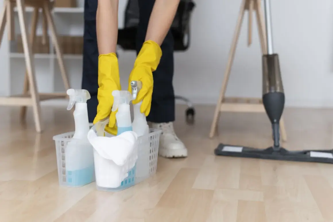 Ręce w żółtych rękawiczkach sięgają po butelki z płynem czyszczącym, gotowe do usunięcia farby w sprayu.