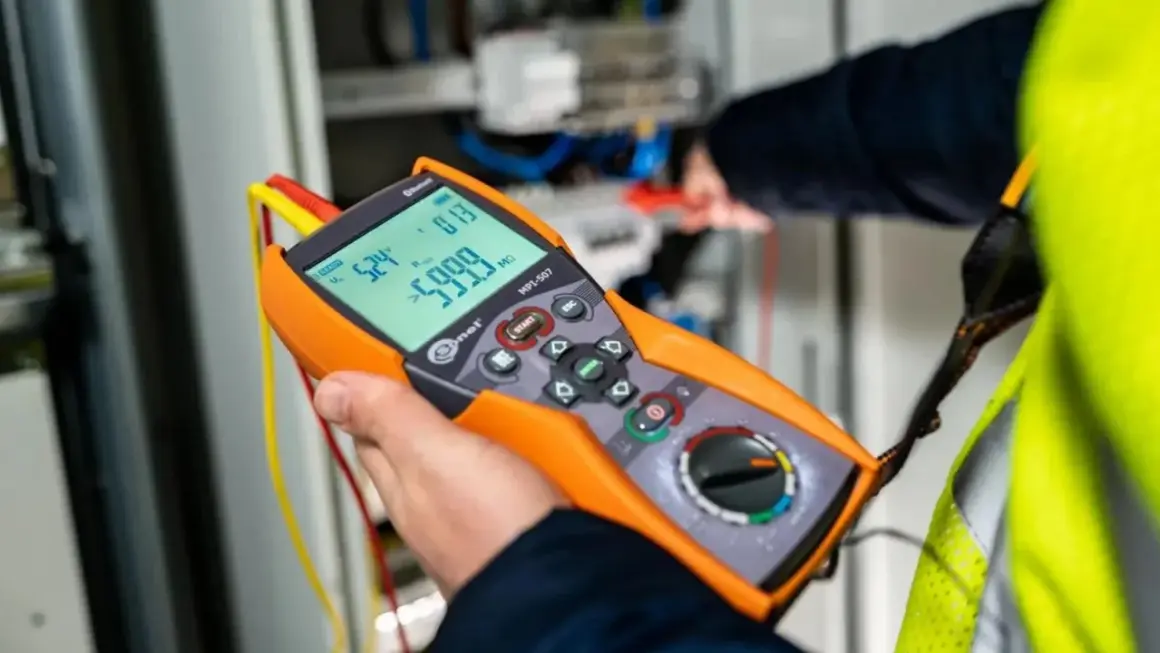 Elektryk wykonuje pomiary elektryczne krok po kroku za pomocą miernika.