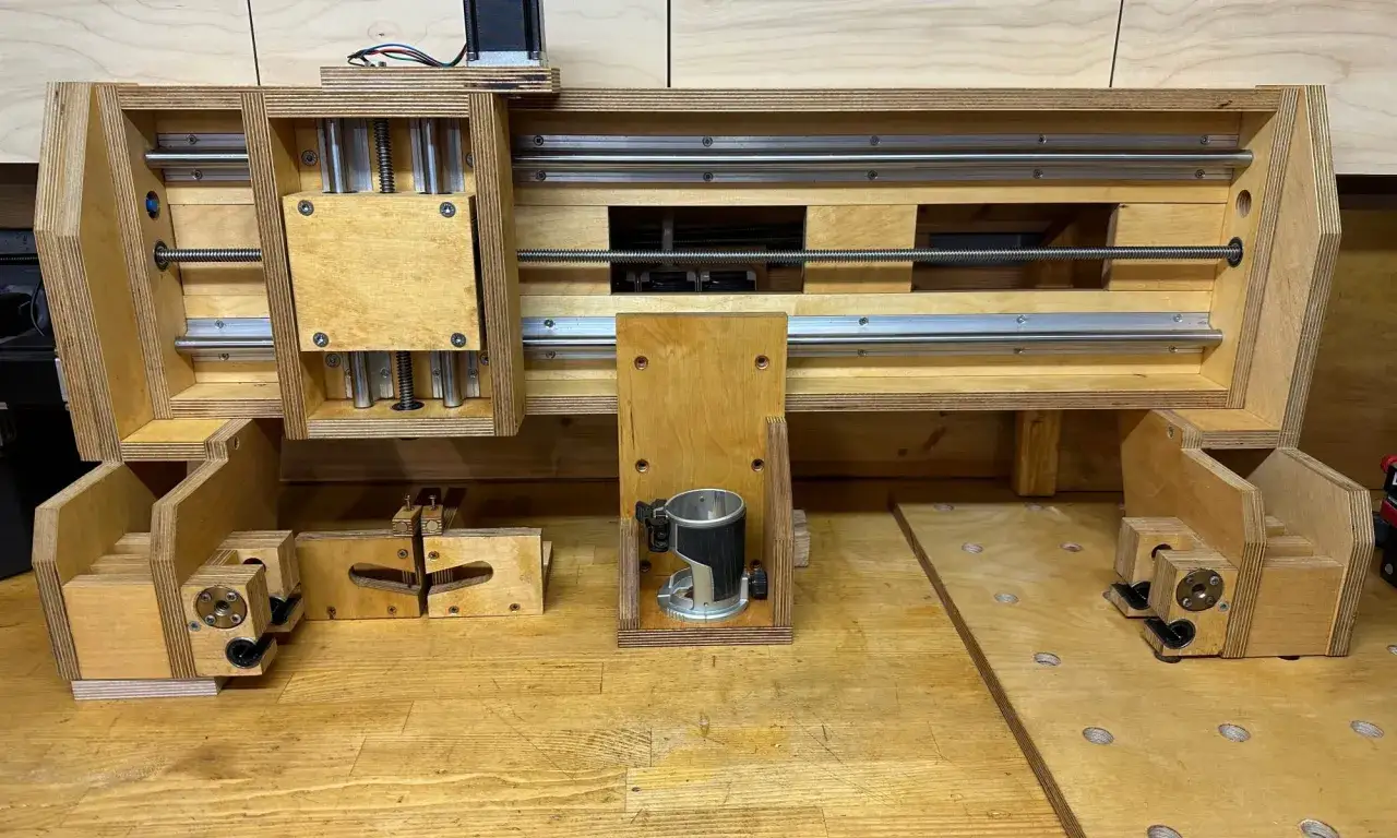Domowa budowa frezarki CNC z drewna i profili aluminiowych. Widoczny frez, śruby pociągowe i prowadnice.