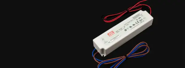 Zasilacz LED z oznaczeniami napięcia i mocy. Urządzenie ma białą obudowę i kable w kolorach czerwonym, czarnym, brązowym i niebieskim.