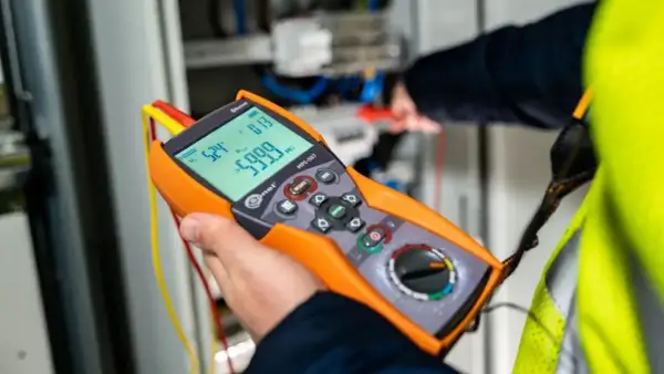 Elektryk wykonuje pomiary elektryczne krok po kroku za pomocą miernika.